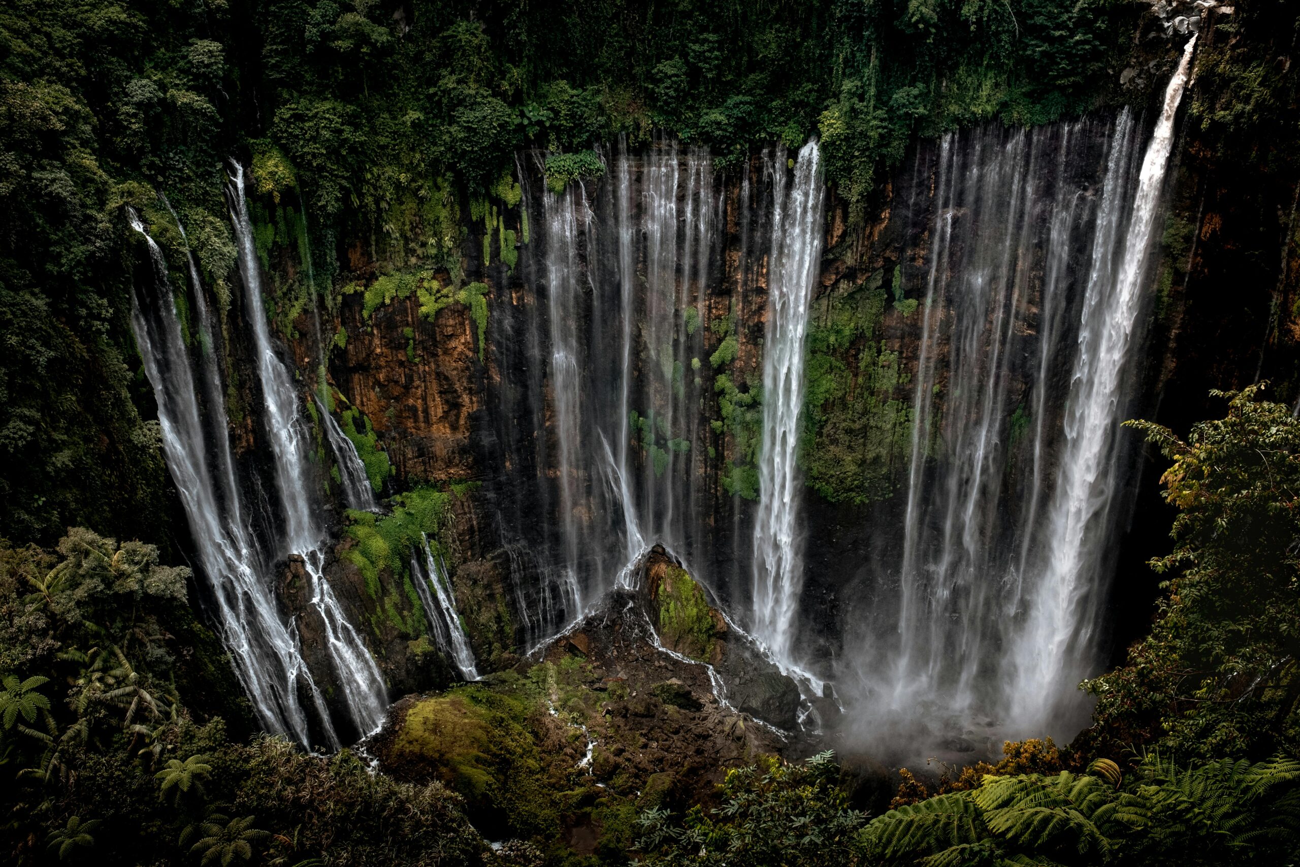 Stunning view of Tumpak Sewu Waterfall cascading in a lush jungle setting in East Java, Indonesia.