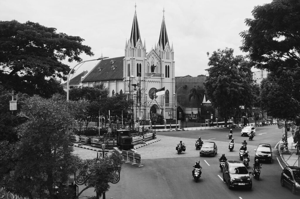 Black and white cityscape featuring traffic and striking church architecture in Malang, Indonesia.