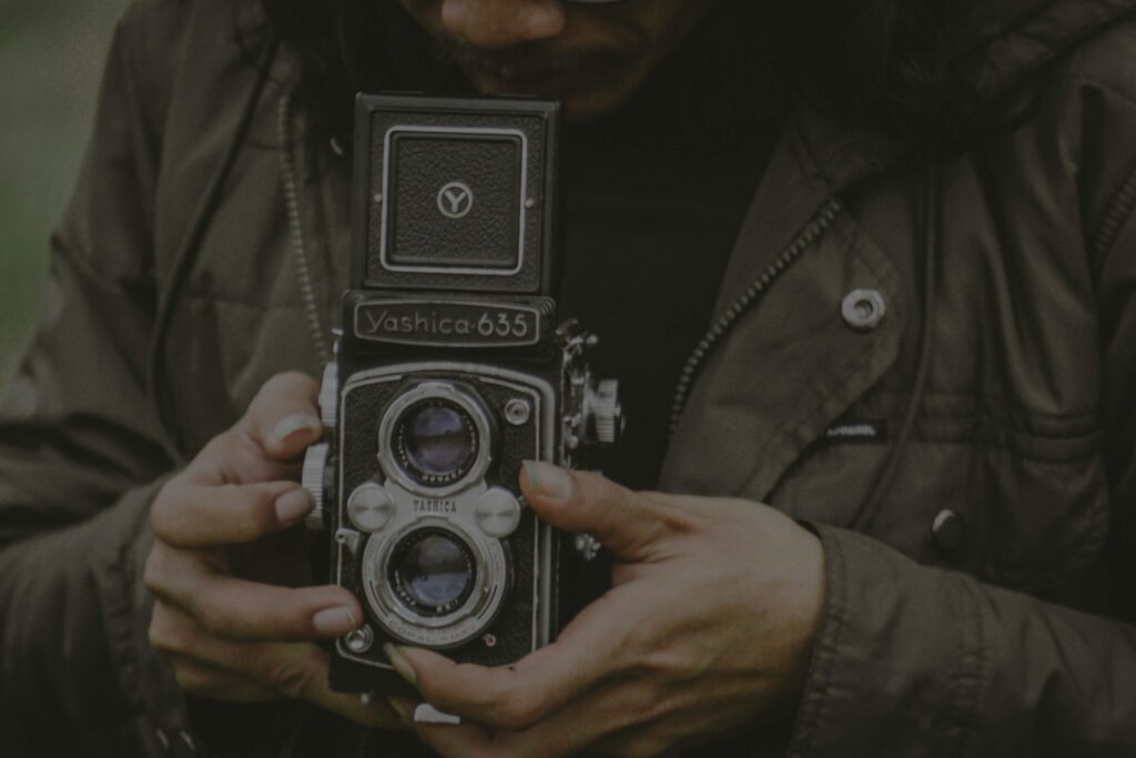 Close-up of hands holding a vintage Yashica 635 camera in Malang, Indonesia.