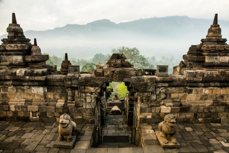 Breathtaking view of Borobudur Temple, Indonesia, surrounded by mist and mountains at sunrise.